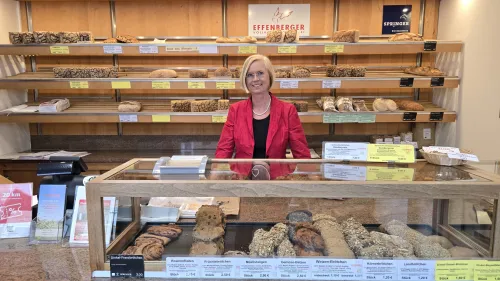 Verkäuferin in rotem Blazer hinter der Brottheke der Effenberger Bäckerei, umgeben von frischem Gebäck.