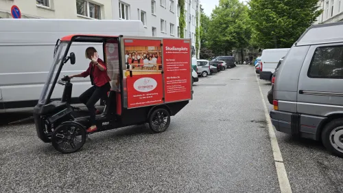 Frau fährt mit E-Cargobike der Bäckerei Effenberger durch eine Wohnstraße – umweltfreundlich und lokal.