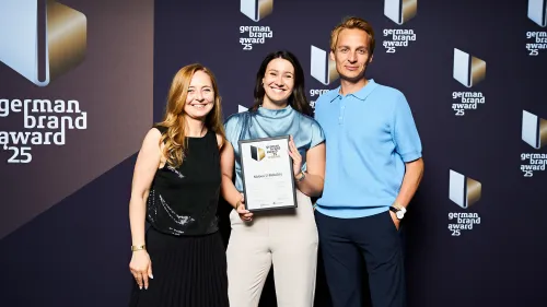 Martina Lewis, Jil Bergmann und Jakub Fukacz halten Preis und Urkunde in die Kamera.