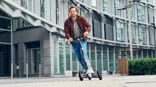 Junger Mann surft mit dem XBoard auf einem Weg durch moderne Gebäude.