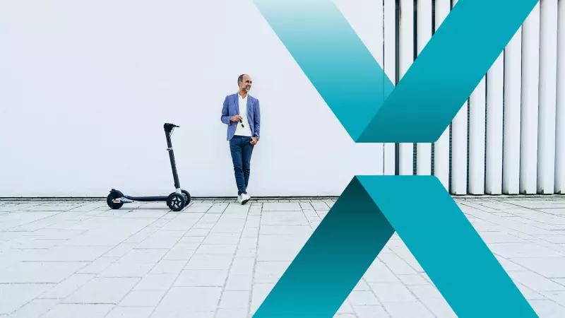 A man in casual clothing is leaning casually against a white wall. Next to him stands a sleek e-scooter on a tiled surface. Large, overlapping teal geometric shapes in the foreground add a modern and dynamic visual element to the image.