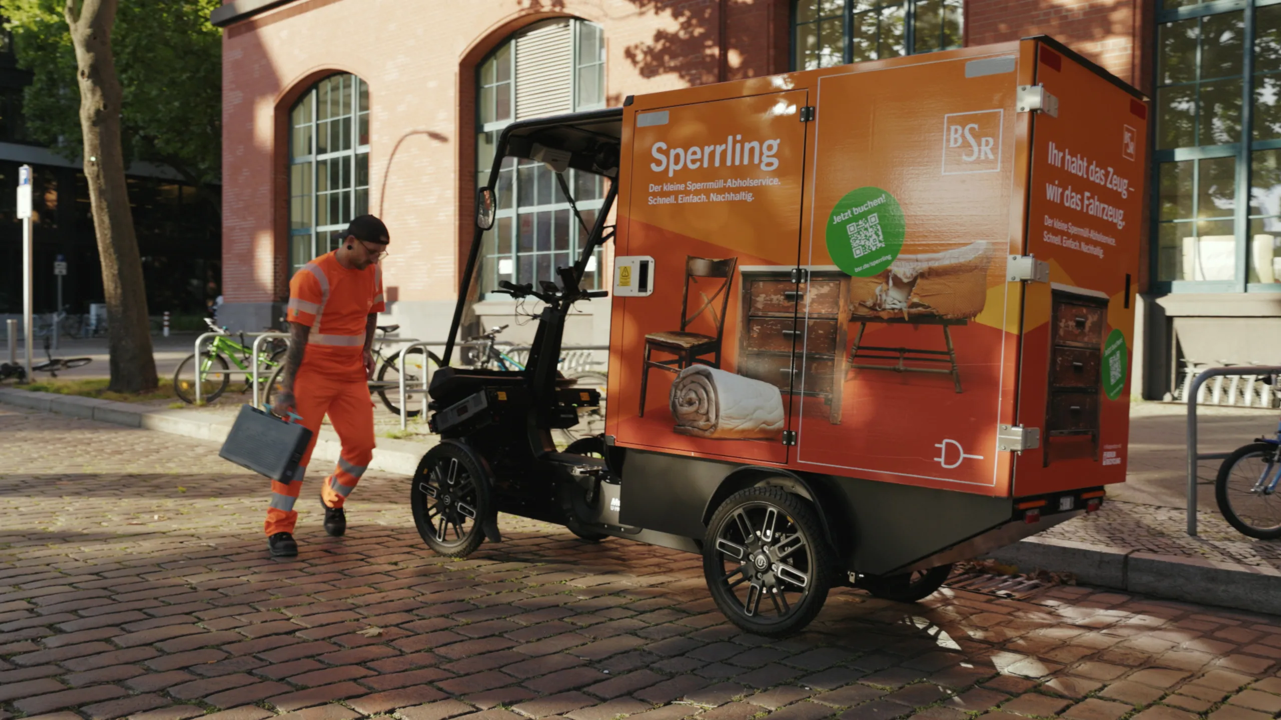 BSR electric cargo bike ‘Sperrling’ on cobblestones; employee with battery next to it