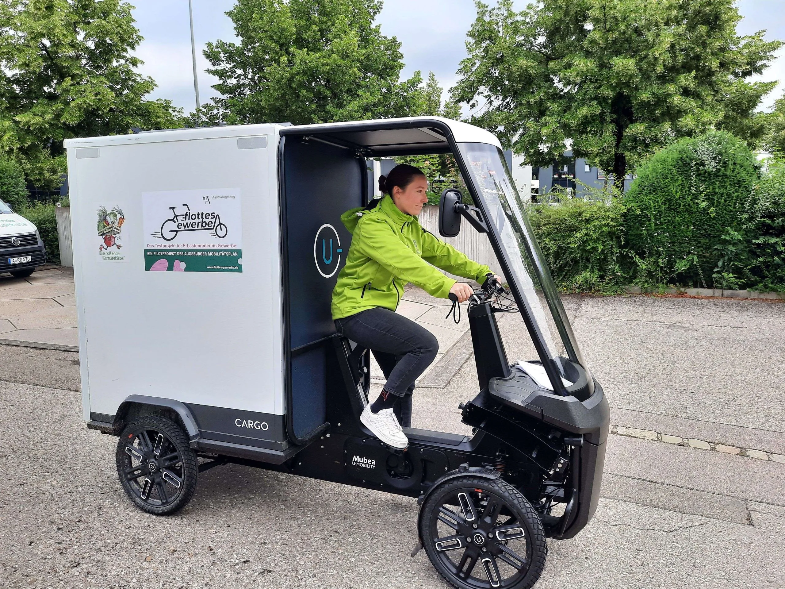 Mitarbeiterin von "Rollende Gemüsekiste" in grüner Jacke testet im Rahmen von "flottes Gewerbe" das Cargo PACK