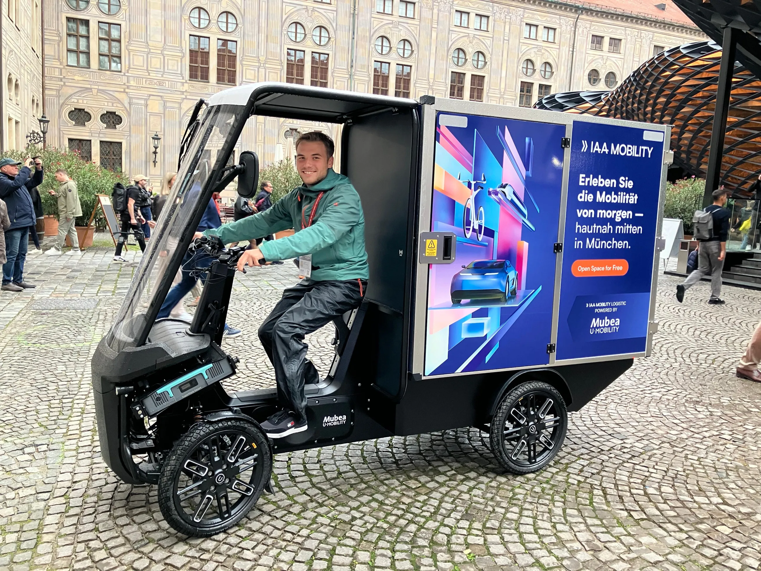 Fahrer im Mubea E-Cargobike mit IAA-Branding auf dem Münchner Messegelände.