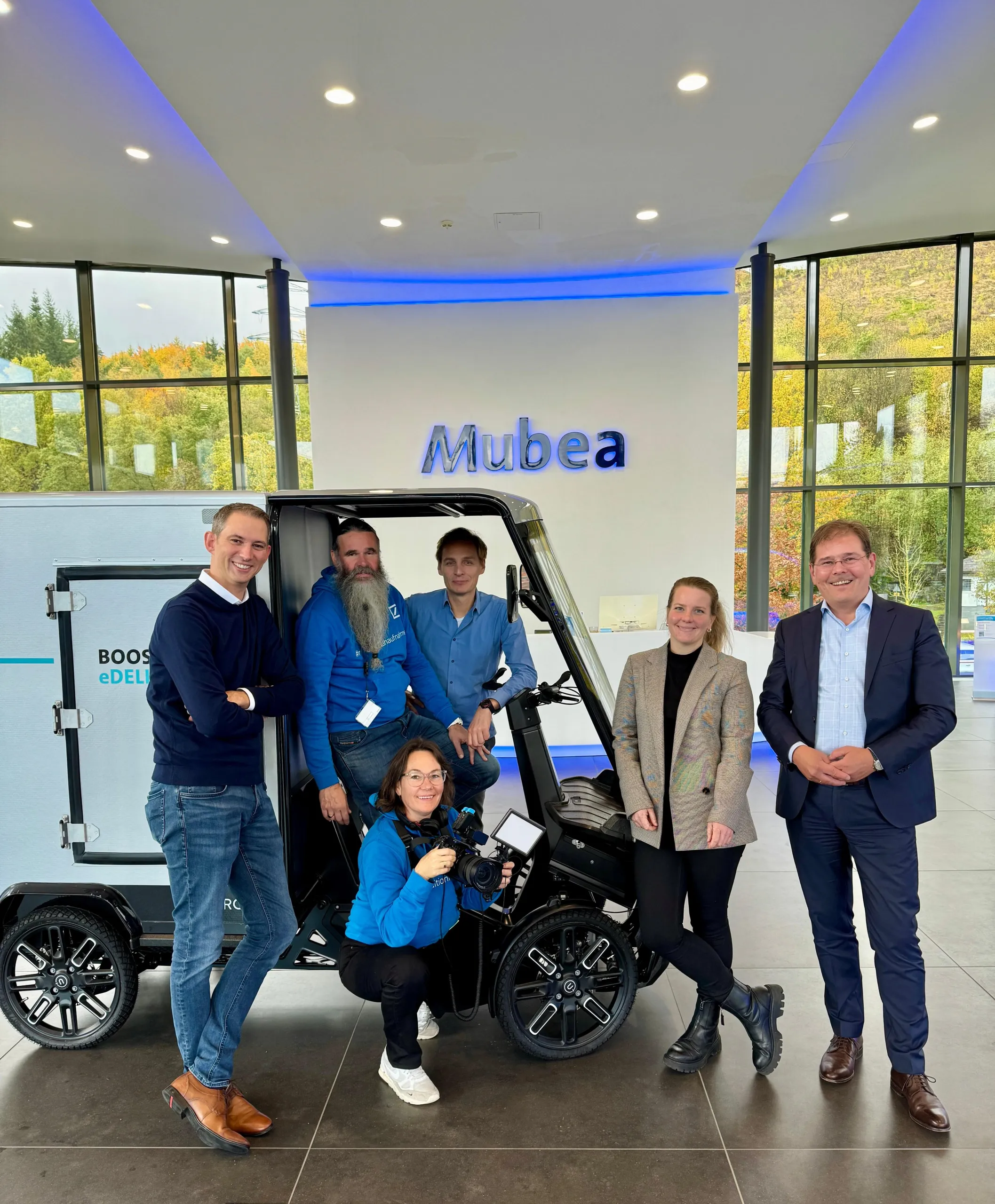 Gruppenfoto vor einem eCargobike in der Mubea Lobby: Filmteam und Mubea-Team gemeinsam.
