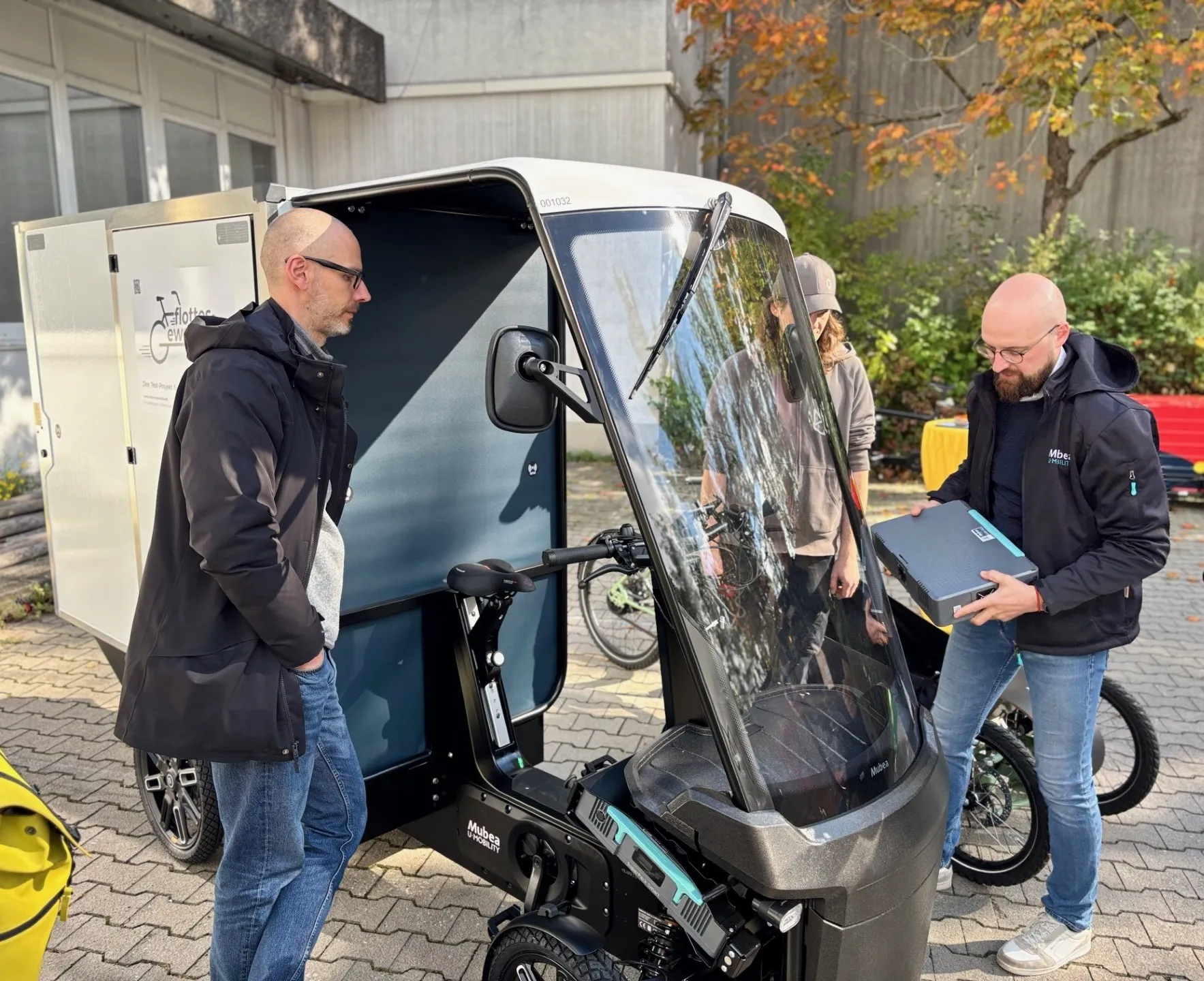 Junge Herren am Cargobike mit Akku in der Hand. 