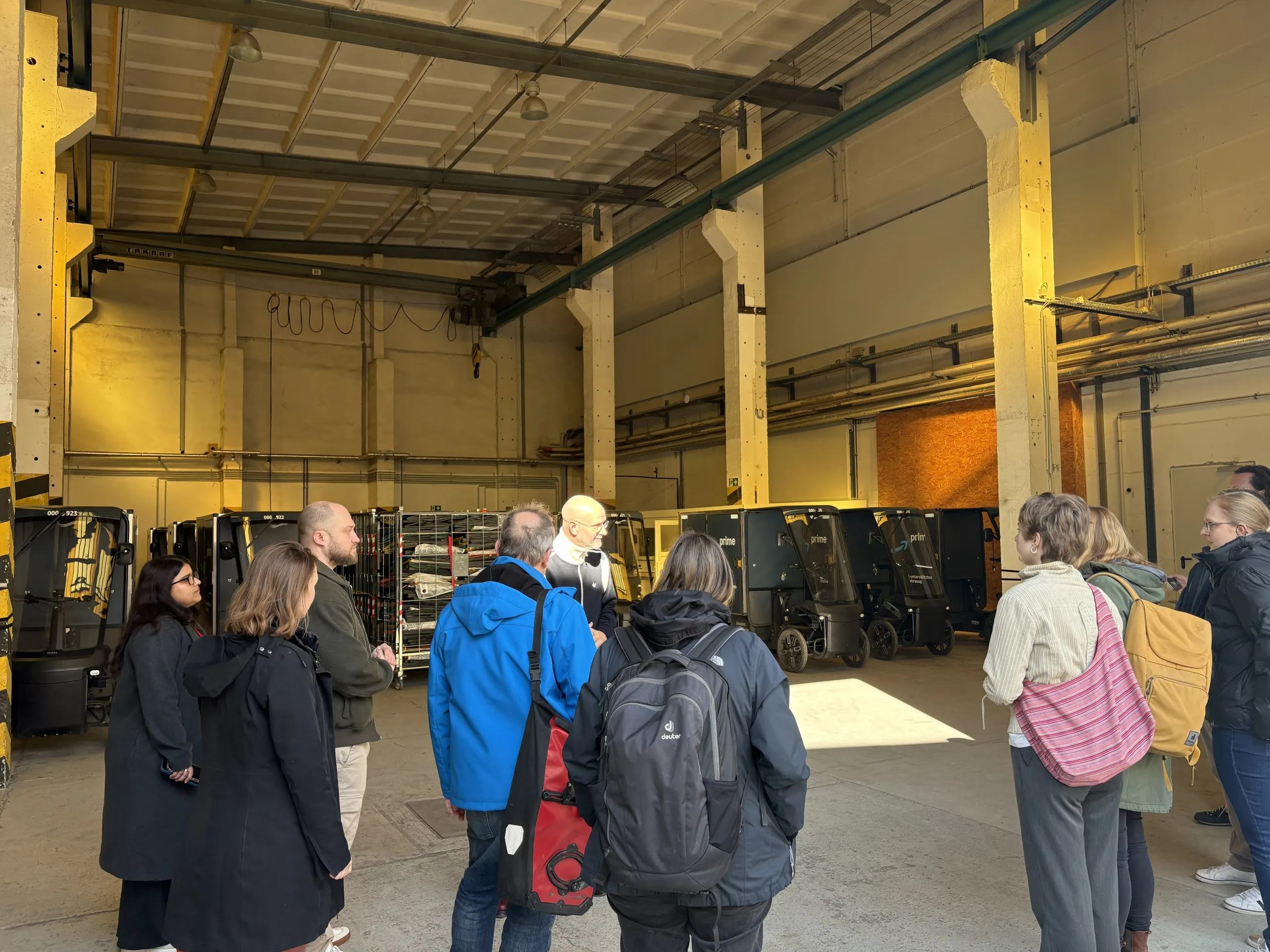 Besuchergruppe im Microhub mit Cargobikes und Logistikfahrzeugen in Berlin