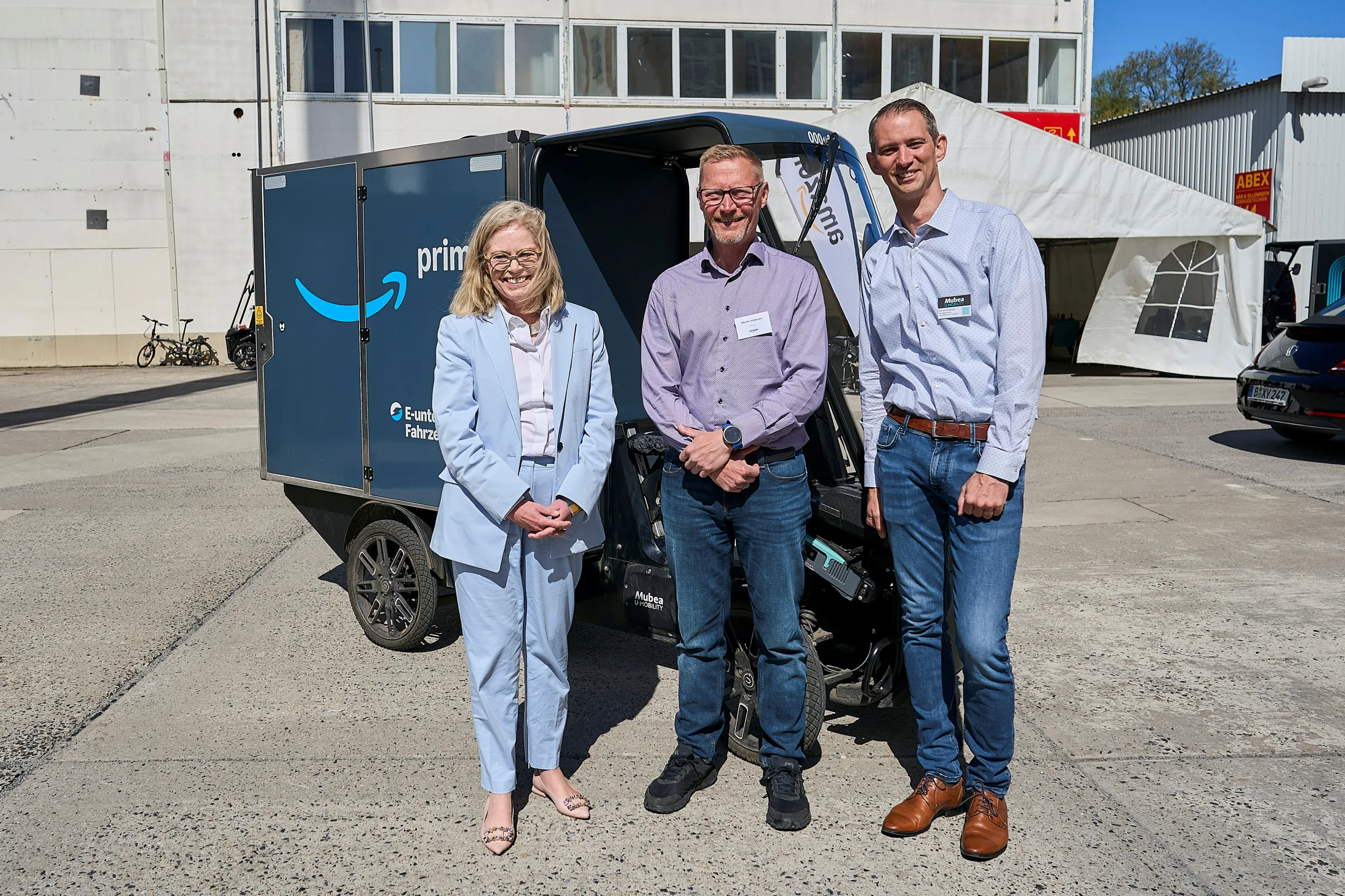 Drei Personen vor einem Mubea E-Cargobike mit Amazon-Branding.