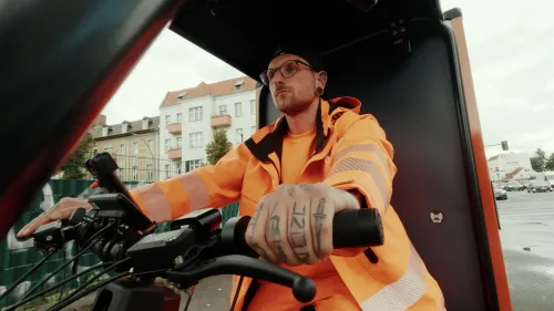 BSR employee rides the orange Mubea cargo bike ‘Sperrling’ to collect bulky waste.