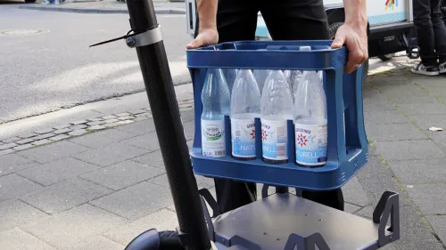 Digital X 2024: Wasserkiste wird auf passende Vorrichtung auf E-Scooter gestellt