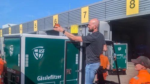 Mitarbeiter U-Mobility und Mitarbeiter der Abfallwirtschaft und Stadtreinigung Freiburg GmbH mit Cargo PACK, das grün foliert ist und auf dem "Gässleflitzer" steht