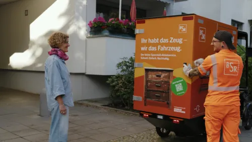 BSR employee closes the rear door of an orange Mubea cargo bike ‘Sperrling’
