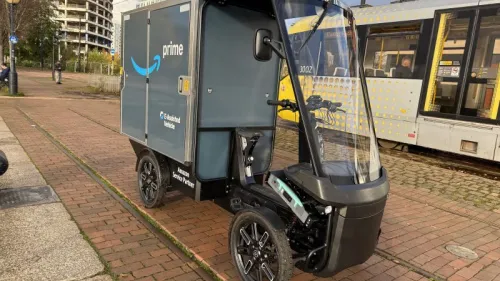 Amazon-Cargobike auf Backsteinweg in Manchester, im Vordergrund, daneben eine gelbe Straßenbahn.