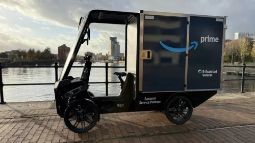 Amazon-Cargobike am Hafen von Manchester, im Profil vor Wasser und städtischer Kulisse.