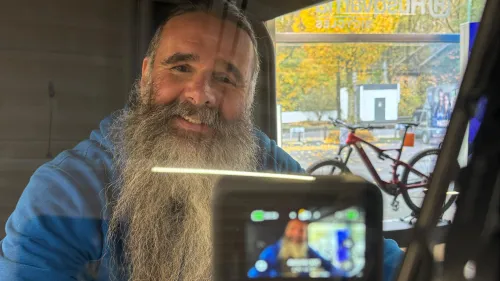 Mann mit langem Bart wird im eCargobike gefilmt; Kamera zeigt sein Gesicht im Display.