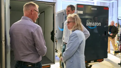 Drei Personen besichtigen den Laderaum eines Amazon E-Cargobikes von Mubea.