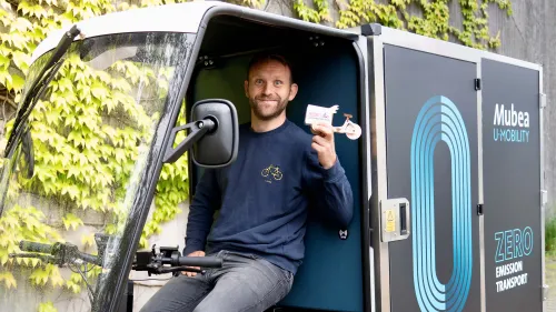 Konrad Martin sitzt im Mubea E-Cargobike und hält eine Karte des B2B Lastenrad Zentrums