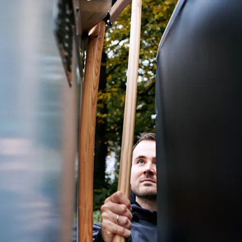 Arbeiter nimmt einen Besen aus der Halterung des E-Cargobikes.