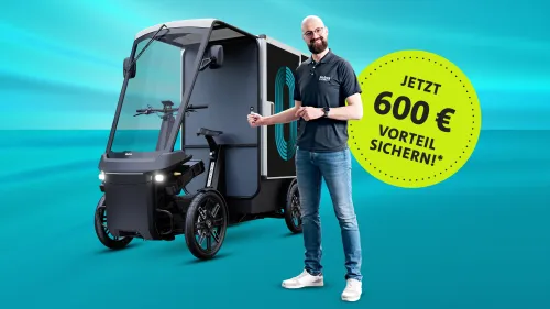 Mann präsentiert ein elektrisches Lastenfahrzeug neben einem Hinweis auf 600 Euro Preisvorteil*