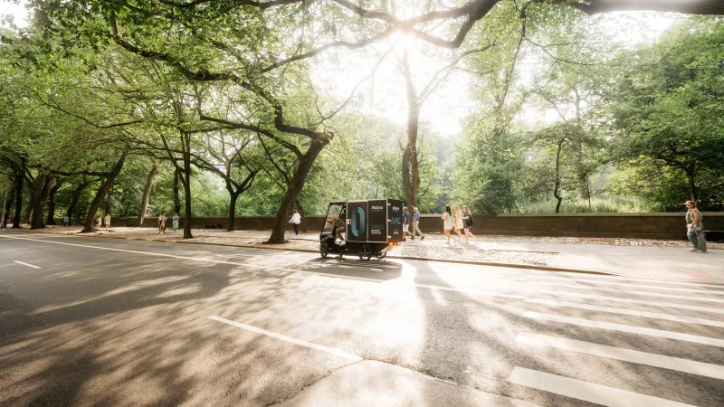 PACK fährt durch grünen Park entlang eines Fußgängerweges.